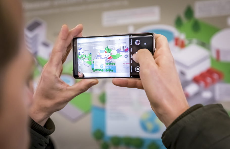 Homme photographiant sur son téléphone portable une affiche sur le projet d'assainissement du CSL Behring Bern.
